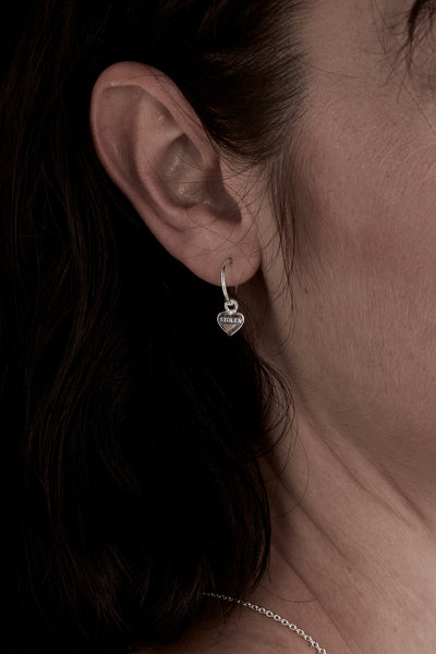 STOLEN GIRLFRIENDS CLUB STOLEN HEART ANCHOR SLEEPER  The Stolen Girlfriends Club Stolen Heart Anchor Sleepers are gorgeous half hoop stud-style, each suspending a mini heart, which features signature 'Stolen' engraving across the front.  These sleepers are great for every day wear. Crafted using sterling silver, pair these with the matching studs, other sleepers or wear alone.