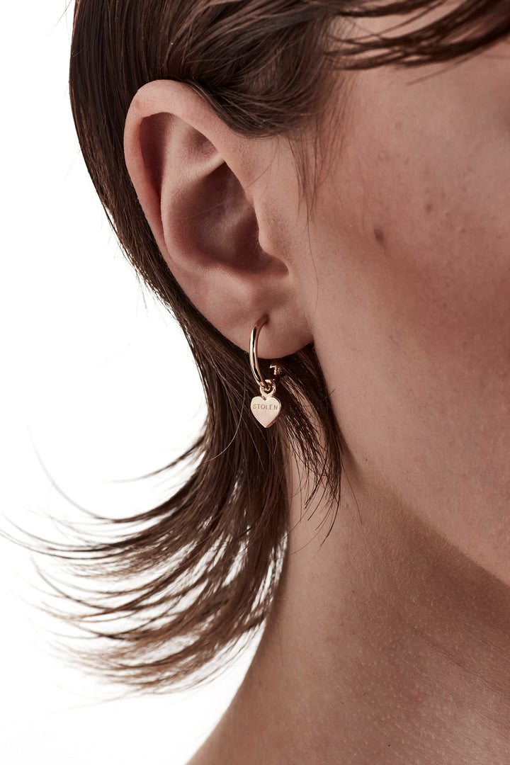 STOLEN GIRLFRIENDS CLUB STOLEN HEART ANCHOR SLEEPER  The Stolen Girlfriends Club Stolen Heart Anchor Sleepers are gorgeous half hoop stud-style, each suspending a mini heart, which features signature 'Stolen' engraving across the front.  These sleepers are great for every day wear. Crafted using 18k gold plating, pair these with the matching studs, other sleepers or wear alone.