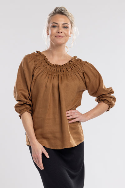 An off the shoulder design with the option to wear up, features a shirred neckline which creates a relaxed drape through the body.  A feminine and fun piece!       Linen/cotton     Shirred neckline     Cuff sleeves 