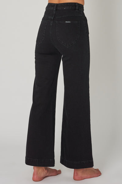 ROLLAS WOMENS SAILOR JEAN - COMFORT JET BLACK  The Rollas Sailor Jeans are now available in Comfort Jet Black, and are a stylish modernised take on classic flares. The Sailor Jeans have a high-waist, and feature a classic zip-to-button closure, with two functional 'sailor style' pockets at the front, and classic signature Rollas branded pockets at the back, finished with wide flared legs. Simple, stylish and easy to wear, team the Rollas Sailor Jeans back with any of your favourite tops this season.