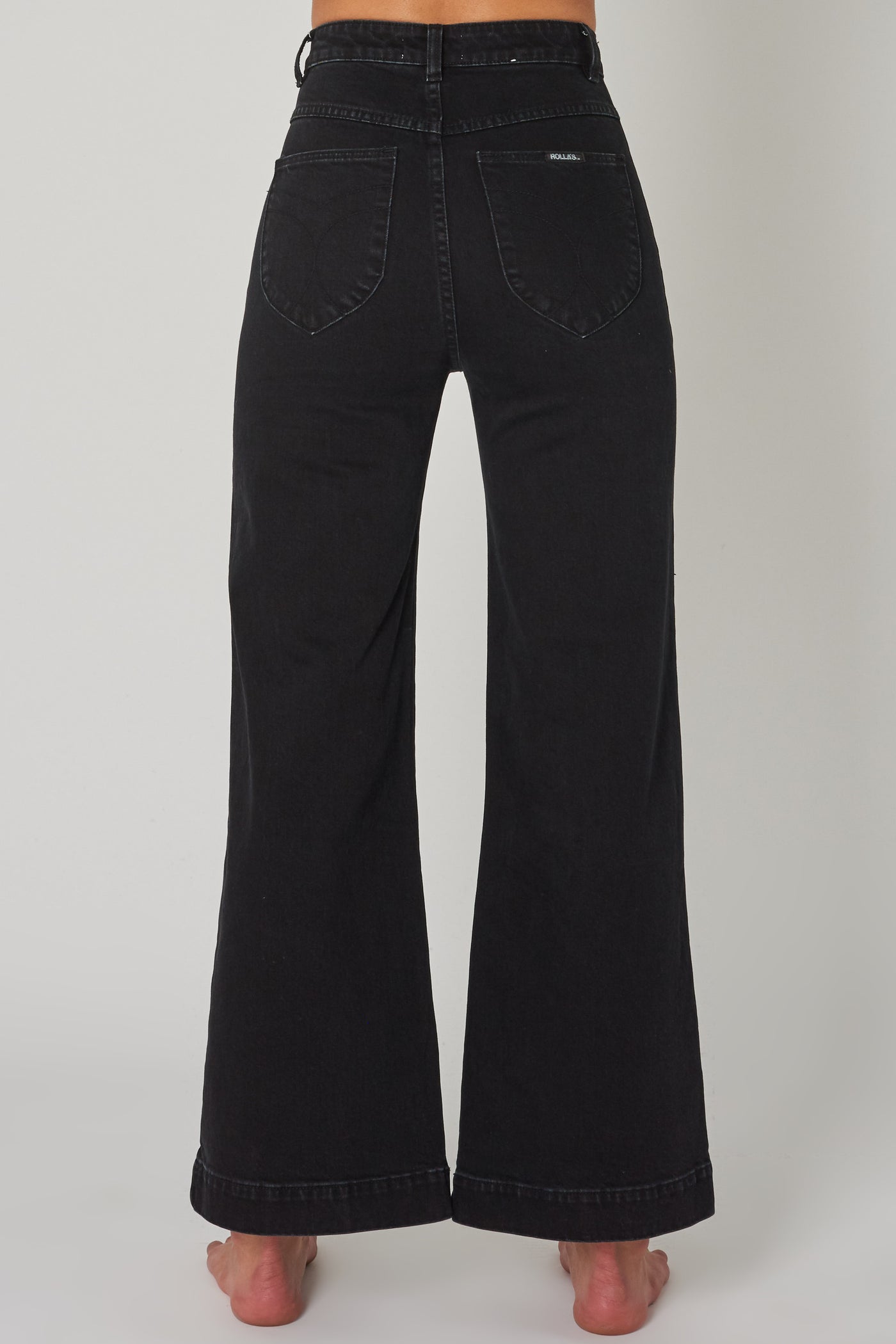 ROLLAS WOMENS SAILOR JEAN - COMFORT JET BLACK  The Rollas Sailor Jeans are now available in Comfort Jet Black, and are a stylish modernised take on classic flares. The Sailor Jeans have a high-waist, and feature a classic zip-to-button closure, with two functional 'sailor style' pockets at the front, and classic signature Rollas branded pockets at the back, finished with wide flared legs. Simple, stylish and easy to wear, team the Rollas Sailor Jeans back with any of your favourite tops this season.