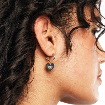 STOLEN GIRLFRIENDS CLUB STOLEN HEART CLUB EARRINGS  The Stolen Girlfriends Club Stolen Heart Sleepers are gorgeous half hoop stud-style, each suspending a heart charm, which features signature 'STOLEN HEARTS FOREVER' engraving across the front.