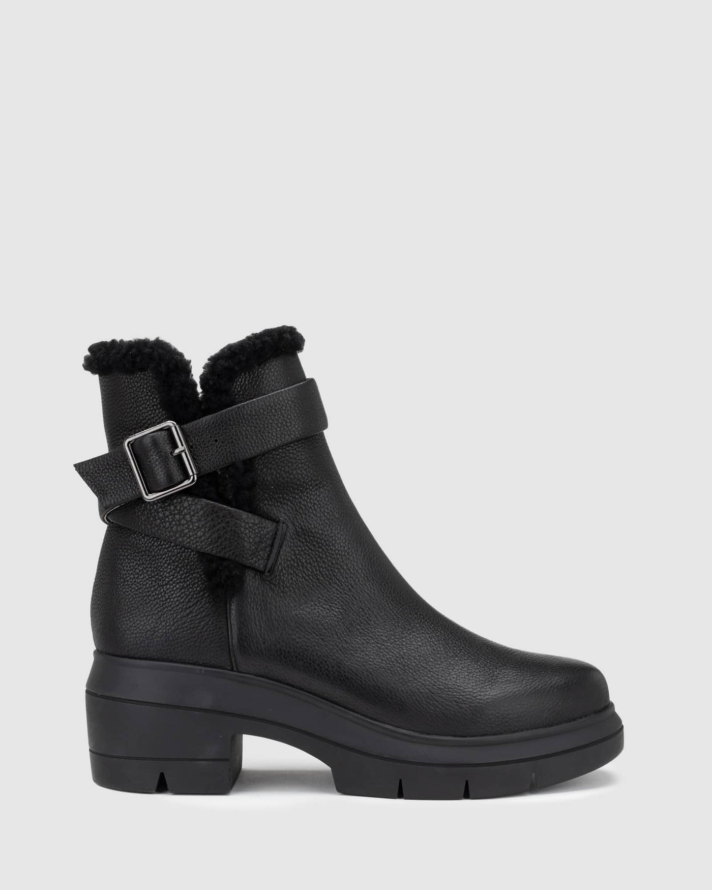 Chaos & Harmony Broadway Boot in black is a comfortable slip on leather boot.  There is black shearling around the top of the boot and the wrap around strap sits around the ankle. Black leather boot with shearling detail and buckle Soft leather lined Black rubber mould outsole